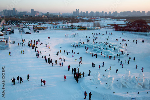 Photography Masses of people sledding in Harbin as the sun sets behind them.