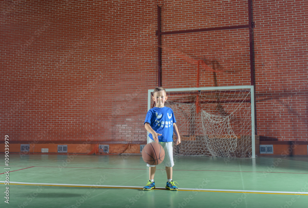 Obraz premium Sporty little boy playing basketball