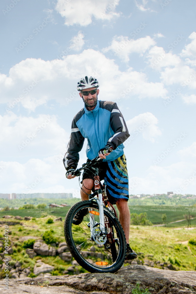man standing on the bike on the edge of a cliff man standing on the bike on the edge of a cliff