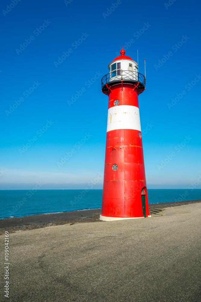 Red and white lighthouse against a bright blue sky Red and white lighthouse against a bright blue sky