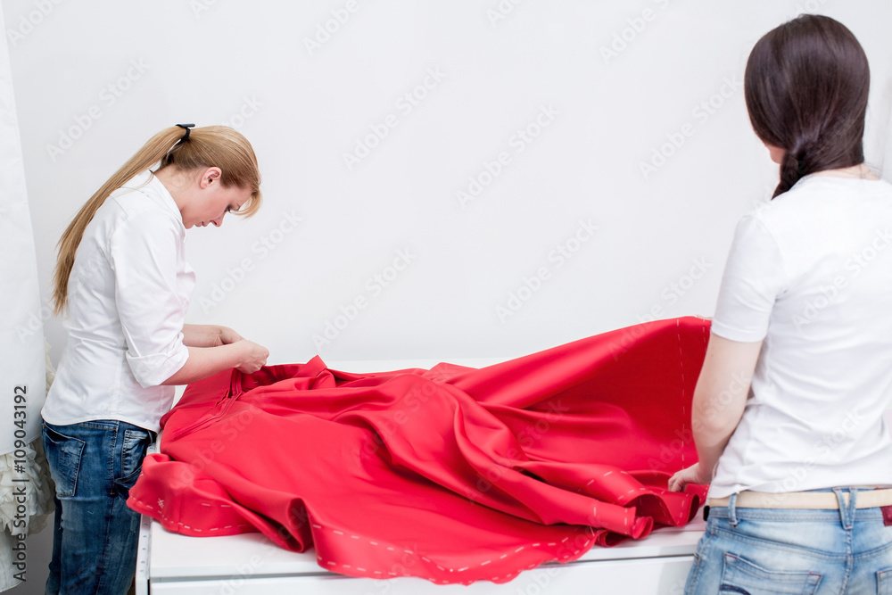 Fototapeta premium tailor sews red dress