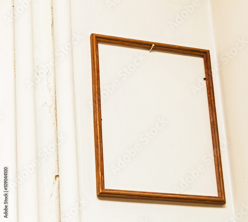 Empty wooden frame on white wall