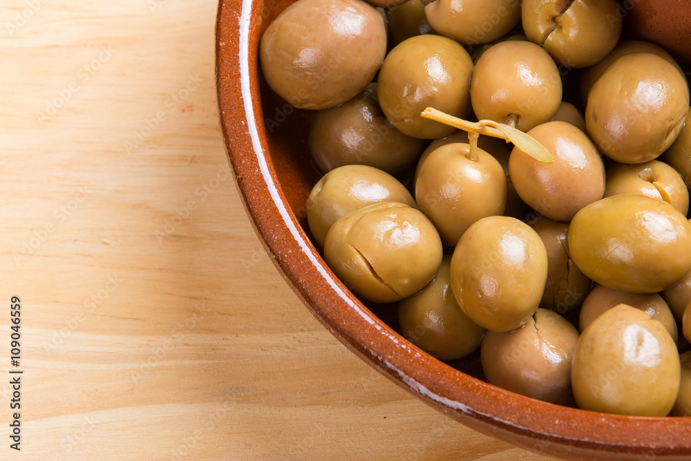 Green olives and seeds on brown ceramic plate.From above Green olives and seeds on brown ceramic plate.From above