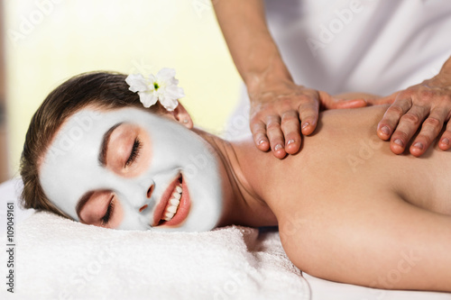 Woman with cly mask enjoying massage. photo