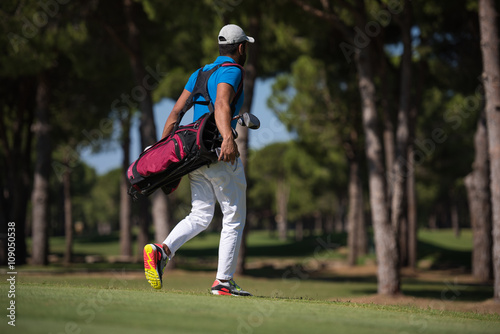 golf player walking and carrying bag photo