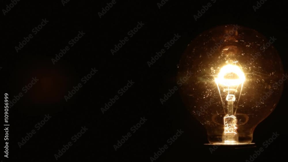 A vintage ball-shaped light bulb being turned on and off. Room for copy-space on the left.