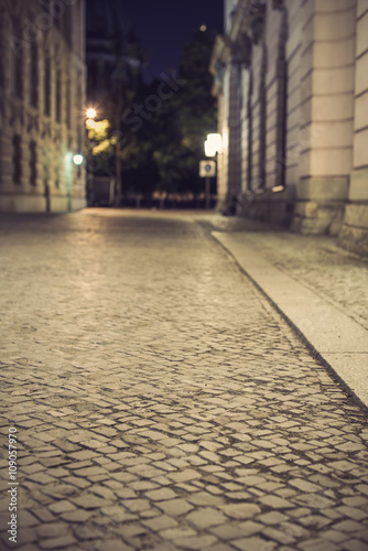 empty brick road at night with blurred background, vintage filtered style, historic midtown of Berlin, Germany, Europe
