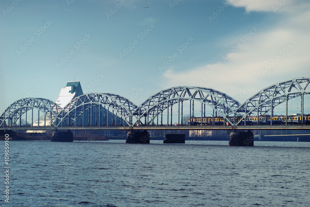 Naklejka premium Train on railway bridge in early spring in Riga