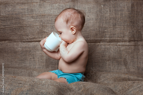 Little baby girl looks into the cup