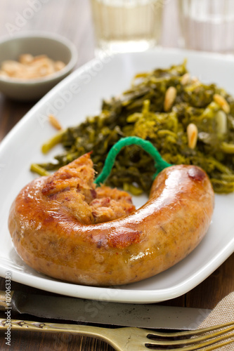 traditional portuguese smoked sausage with turnip greens on white plate on brown background