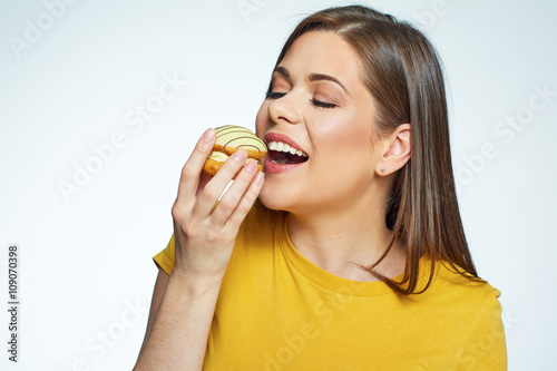 Close up face portrait of happy woman eatin macaron French cake