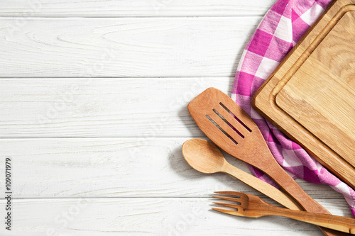 Wooden spoons and other cooking tools with  napkins on the kitchen table.