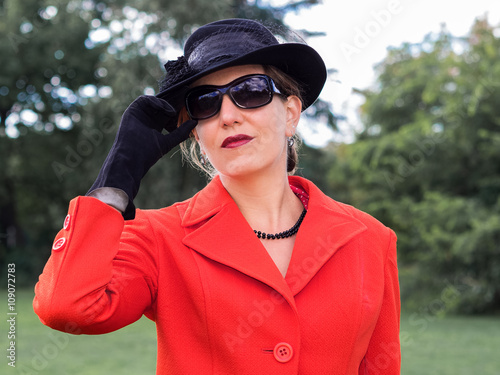 Attraktive Frau in einem rotem Kostüm mi Hut und Sonnenbrille - © arianarama