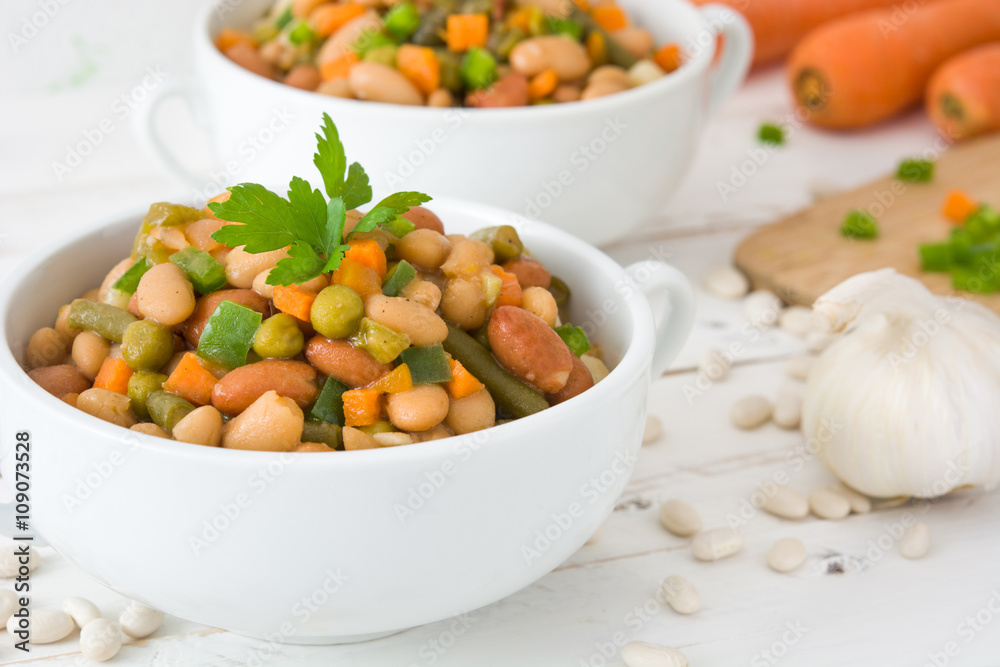 White beans with vegetables on white wood
