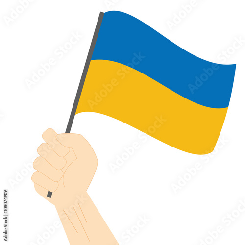 Hand holding and raising the national flag of Ukraine