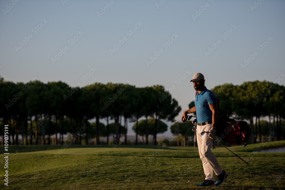 golfer  walking and carrying golf  bag at beautiful sunset