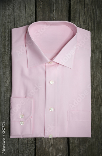 Pink shirt and mobile on wooden background