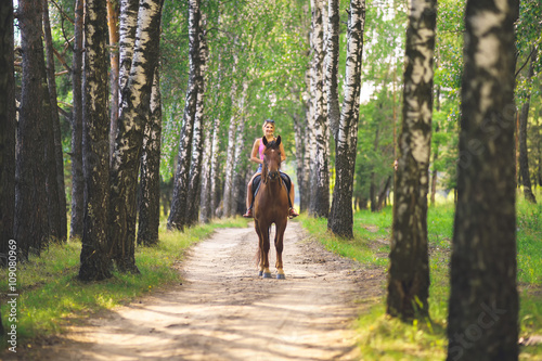 Молодая девушка катается верхом на лошади в  березовом лесу летом © vladimirzhoga