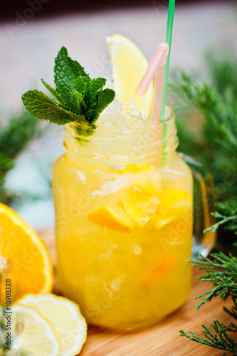 Preparation of the lemonade drink with tubes. Lemonade in the jug with lemons with mint on the table