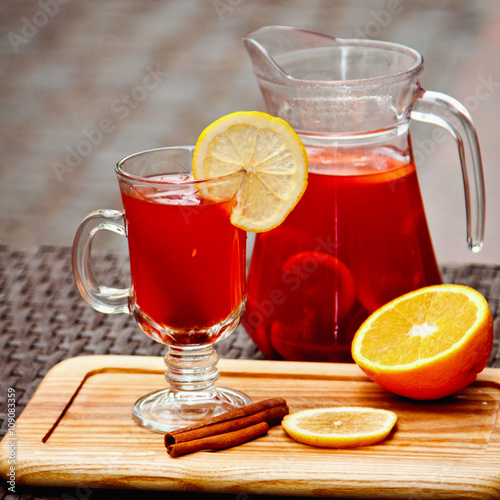 Refreshing summer fruit lemonade with orange and cinnamon in a beautiful glass and jar on wooden background