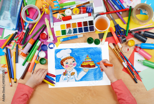 child drawing holiday cake and cook  top view hands with pencil painting picture on paper  artwork workplace