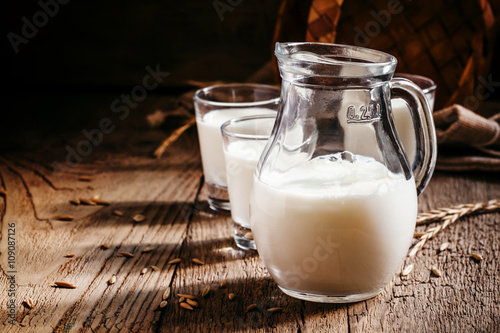 Fresh cow s milk in glass jug  vintage wooden background  still