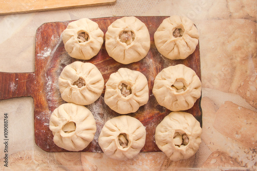 Vak belyash - homemade meat pies on woden chopping board frosted with flour