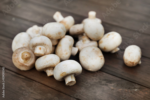 Fresh champignon mushhrooms on a wooden background