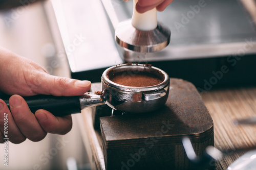 Barista pressing coffee in the machine holder