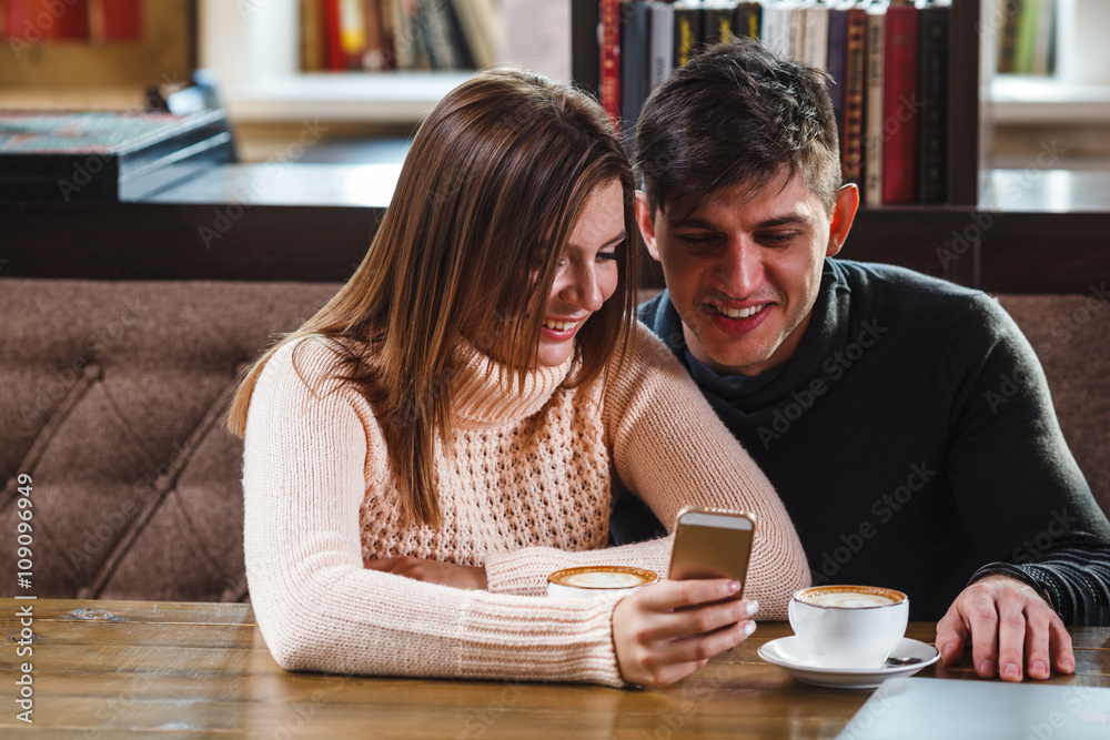 couple in cafe looking at smartphone couple in cafe looking at smartphone