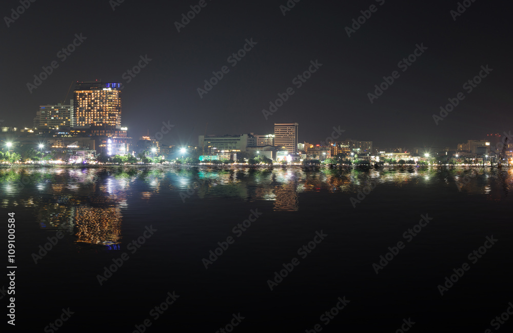 Cityscape of Pattaya beach at night with water reflection