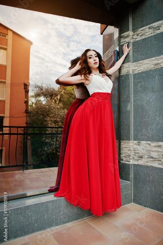 Portrait of fashionable girl at red evening dress posed backgrou © AS Photo Family