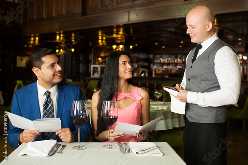 Cheerful couple with menu in a restaurant making order
