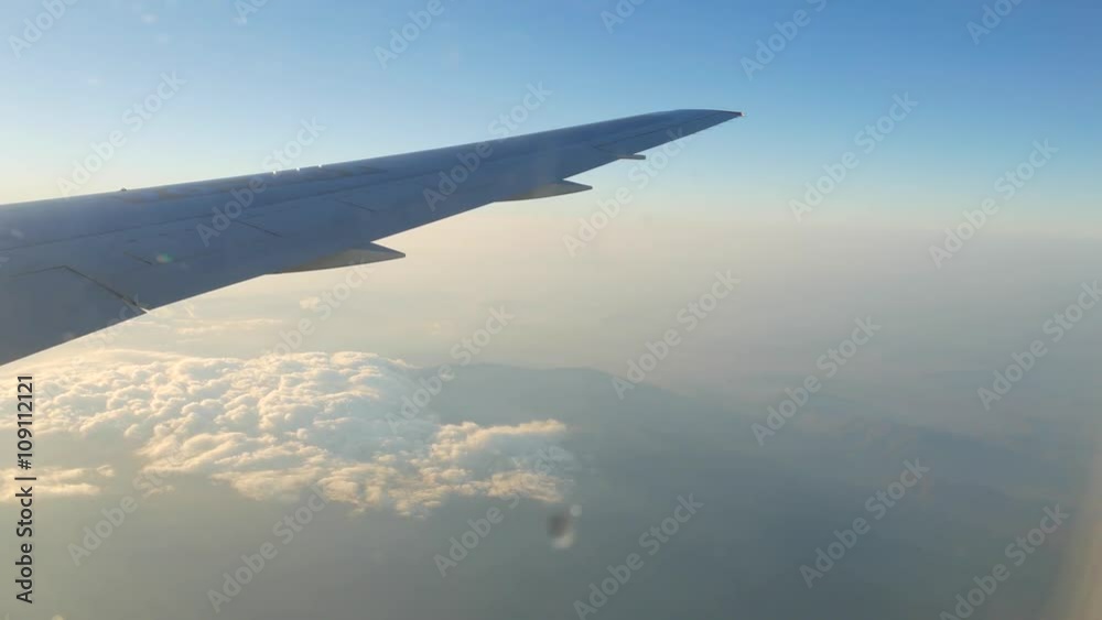 Wing of plane flying over mountains and clouds Wing of plane flying over mountains and clouds