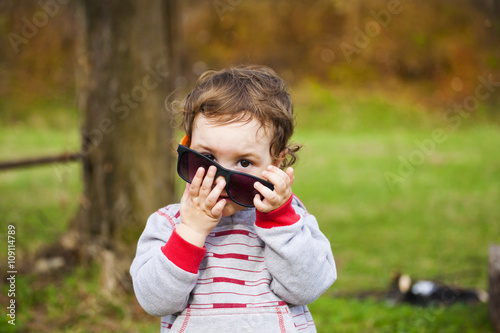 Little boy tries on his mother's glasses.