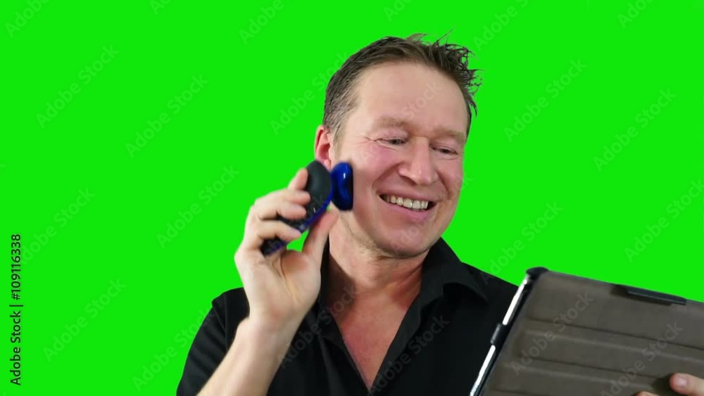 Man shaving and reading news in tablet. Green screen. Man shaving and reading news in tablet. Green screen.