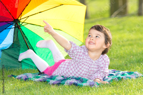 little happy girl with a rainbow umbrella in park