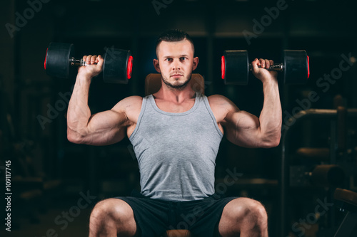 sport, bodybuilding, weightlifting, lifestyle and people concept - young man with dumbbells flexing muscles in gym