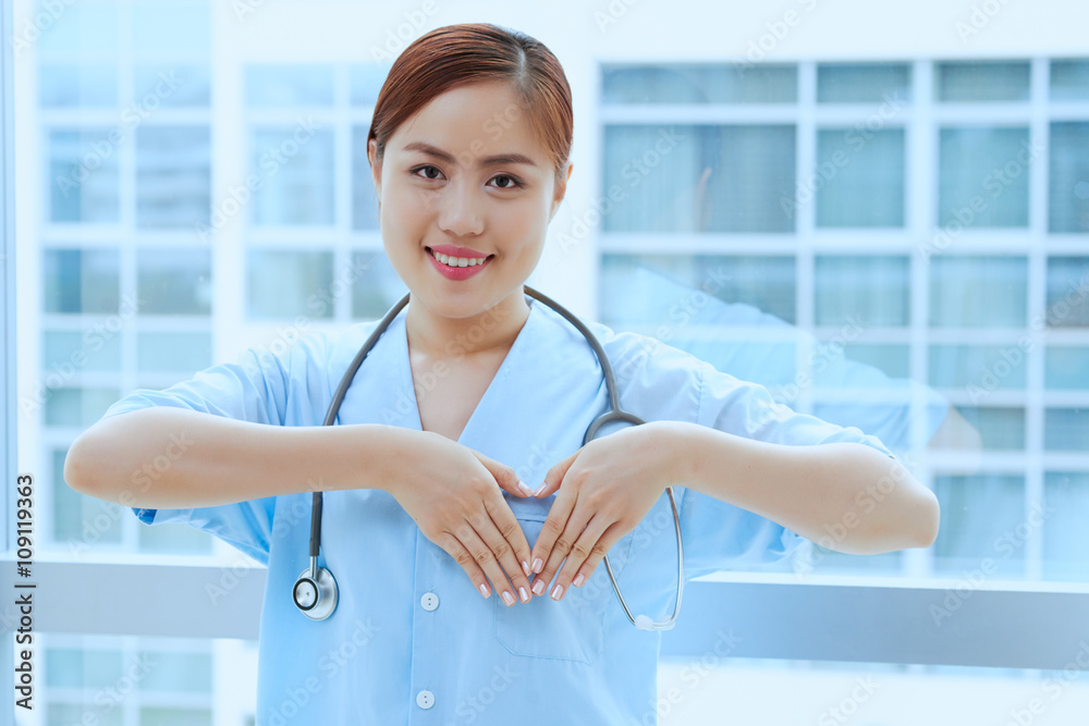 Young Vietnamese cardiologist making heart shape with her hands