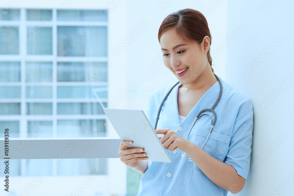 Happy young medical worker reading something on digital tablet Happy young medical worker reading something on digital tablet