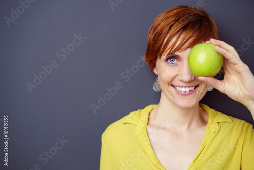 lächelnde frau hält einen grünen apfel in der hand photo