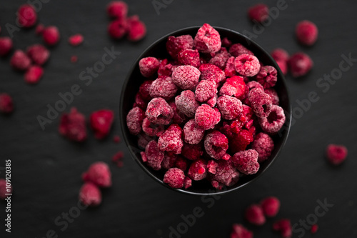 Frozen Raspberries in Bowl, Covered with Ice on Dark Background