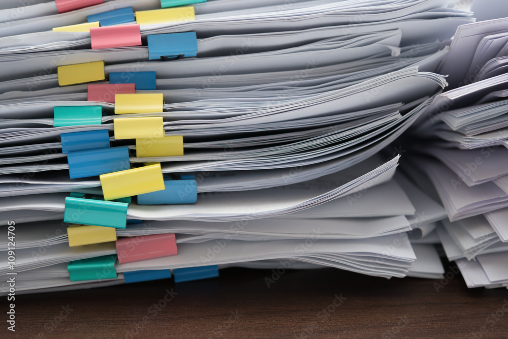 two piles of documents with colorful clips on desk stack up two piles of documents with colorful clips on desk stack up