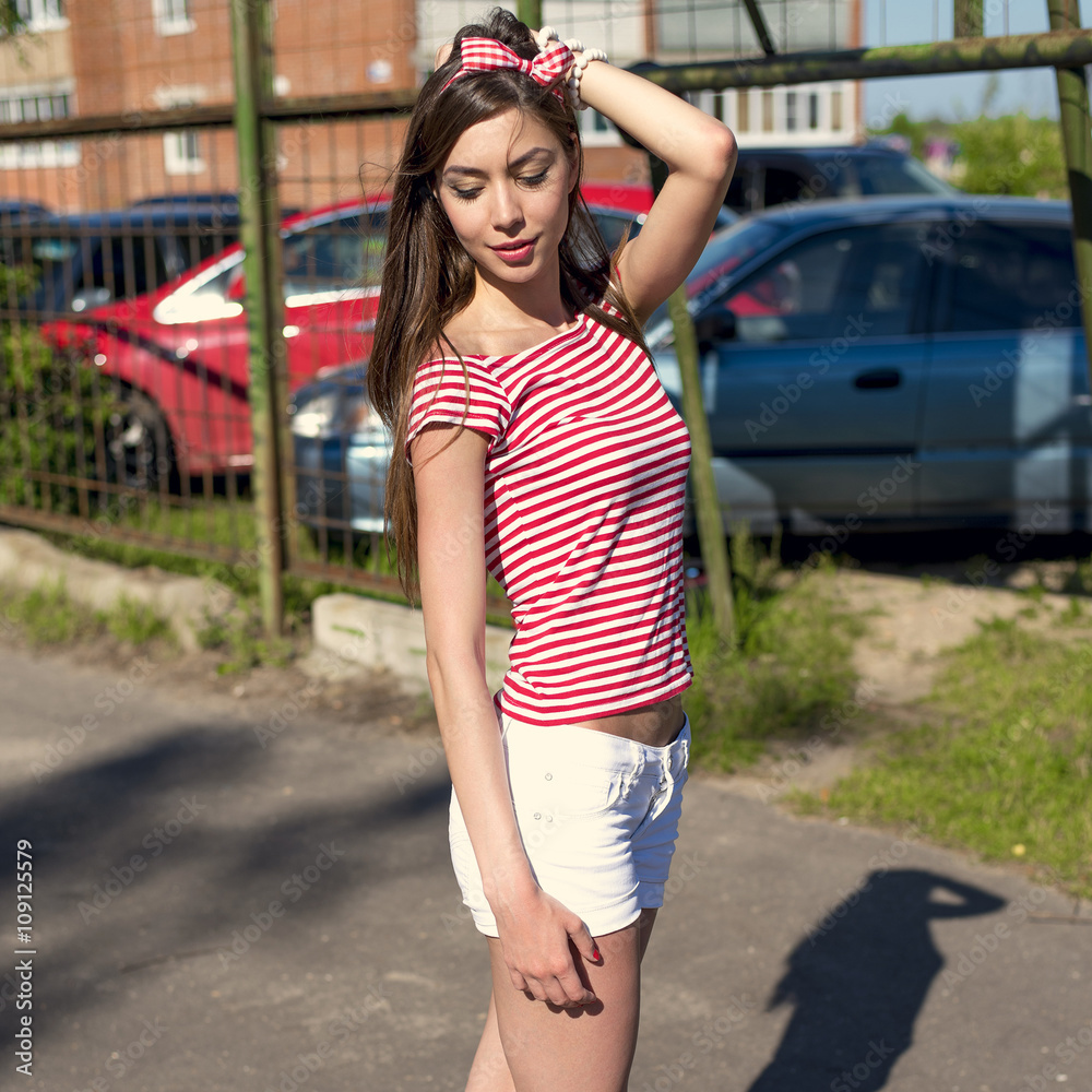 Beautiful girl outdoors on the playground, resting in a bright red T-shirt white shorts Beautiful girl outdoors on the playground, resting in a bright red T-shirt white shorts