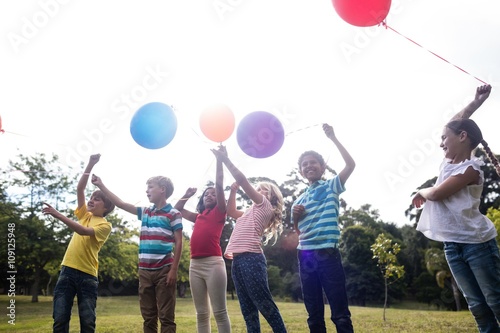 Happy children playing with balloons in the park