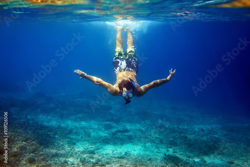 man with mask swimming underwater in tropical sea