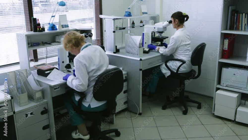 Two Young Scientists Are Exploring With Using a Microscope, Science, Research, Laboratory. Wide Shot Two Young Scientists Are Exploring With Using a Microscope, Science, Research, Laboratory. Wide Shot