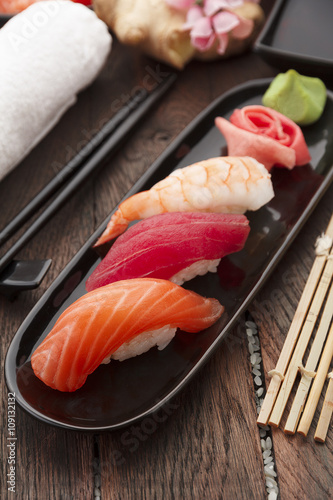 Sushi nigiri set on a black plate over wooden table