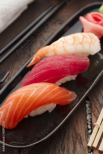 Sushi nigiri set on a black plate over wooden table