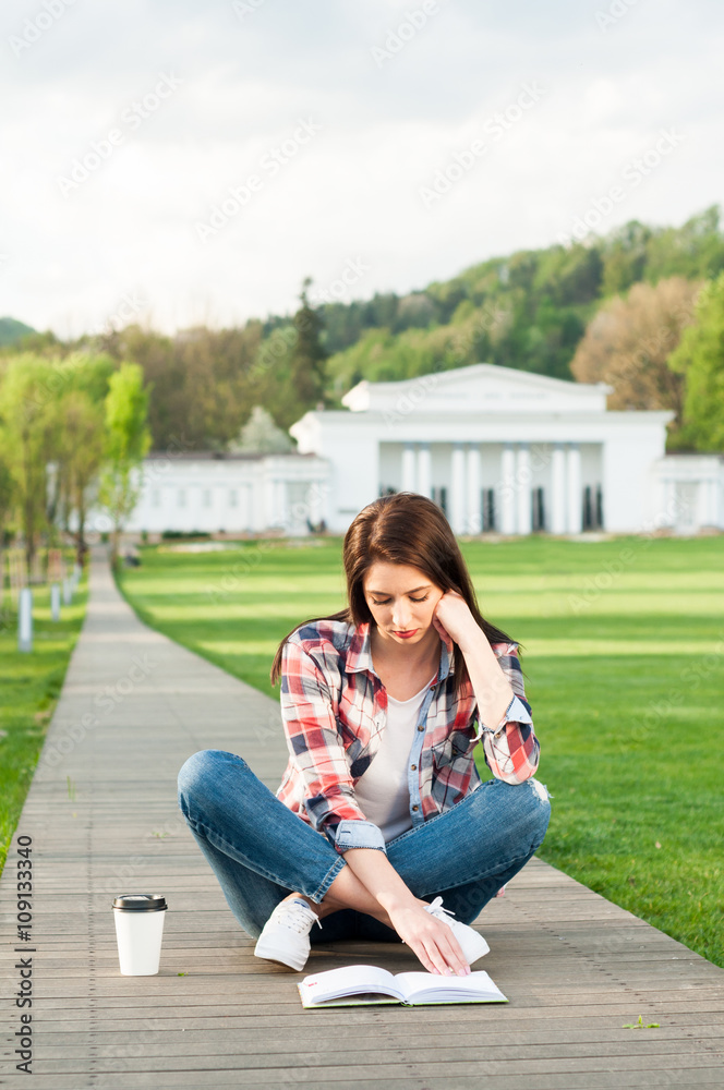 Pretty woman resting in the park with book and coffee Pretty woman resting in the park with book and coffee